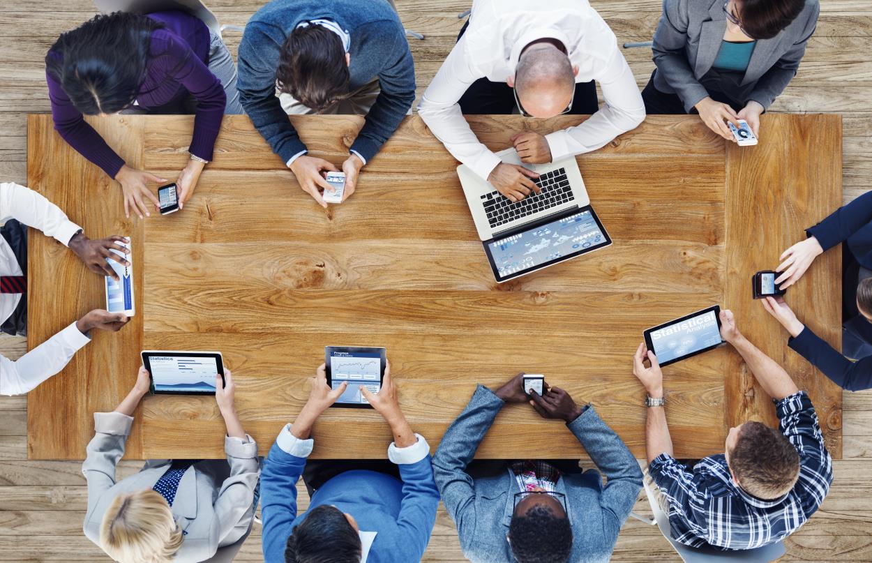 group people around a large table using various devices to look at the internet