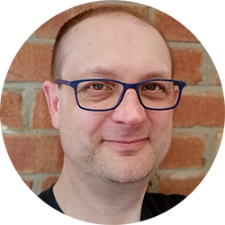 person with glasses smiling at the camera