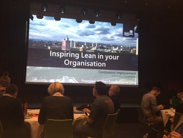 Colour photograph of an audience in a lecture theatre watching a presentation on 'Inspiring Lean in your Organisation'