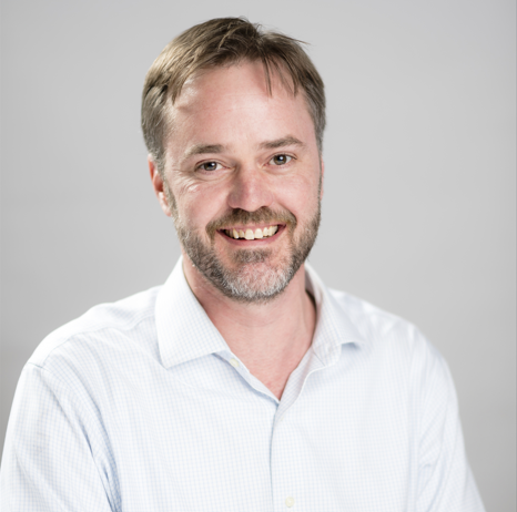 Mark Bonetzky smiling at the camera in a white shirt