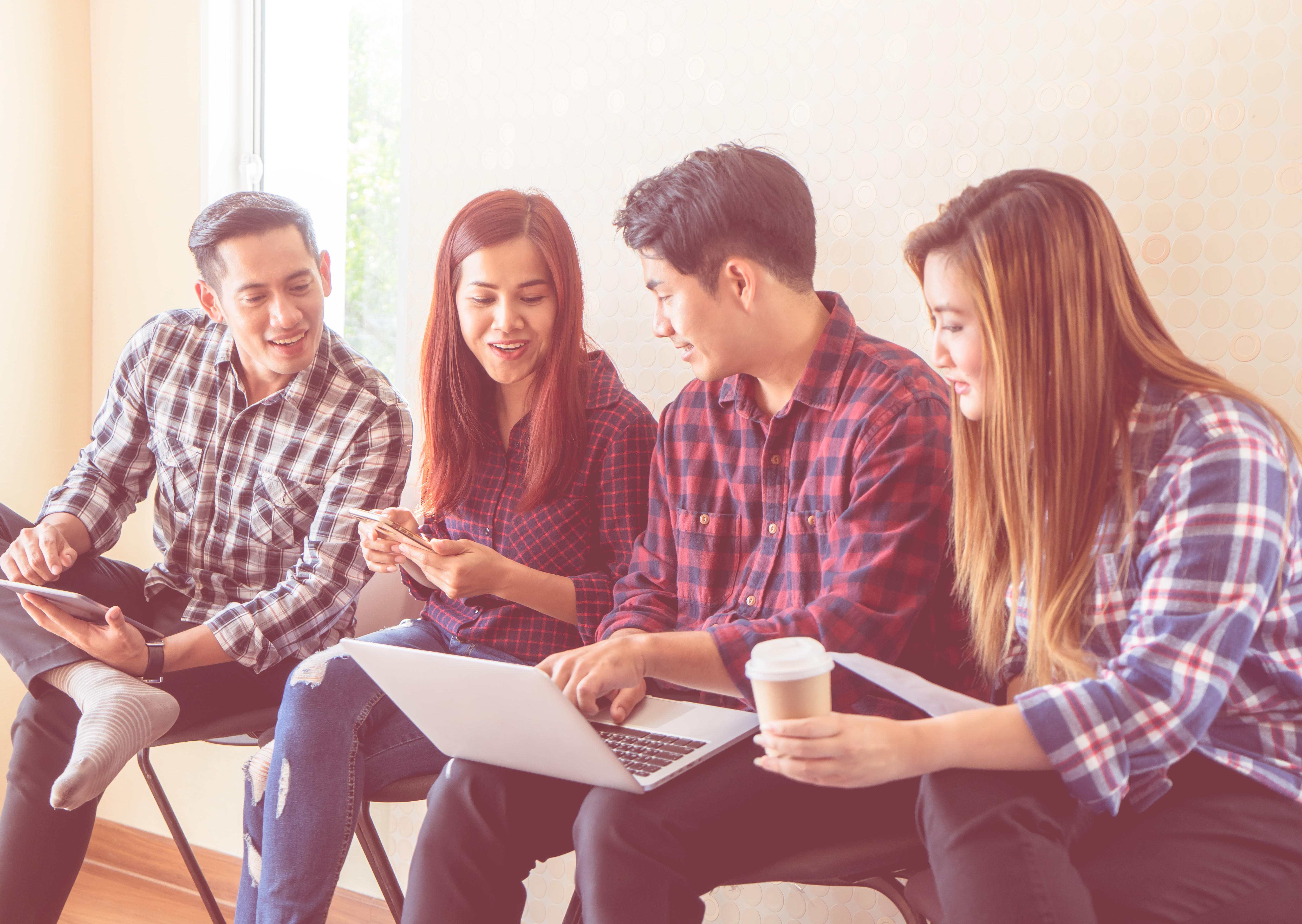 four people sat looking at a laptop