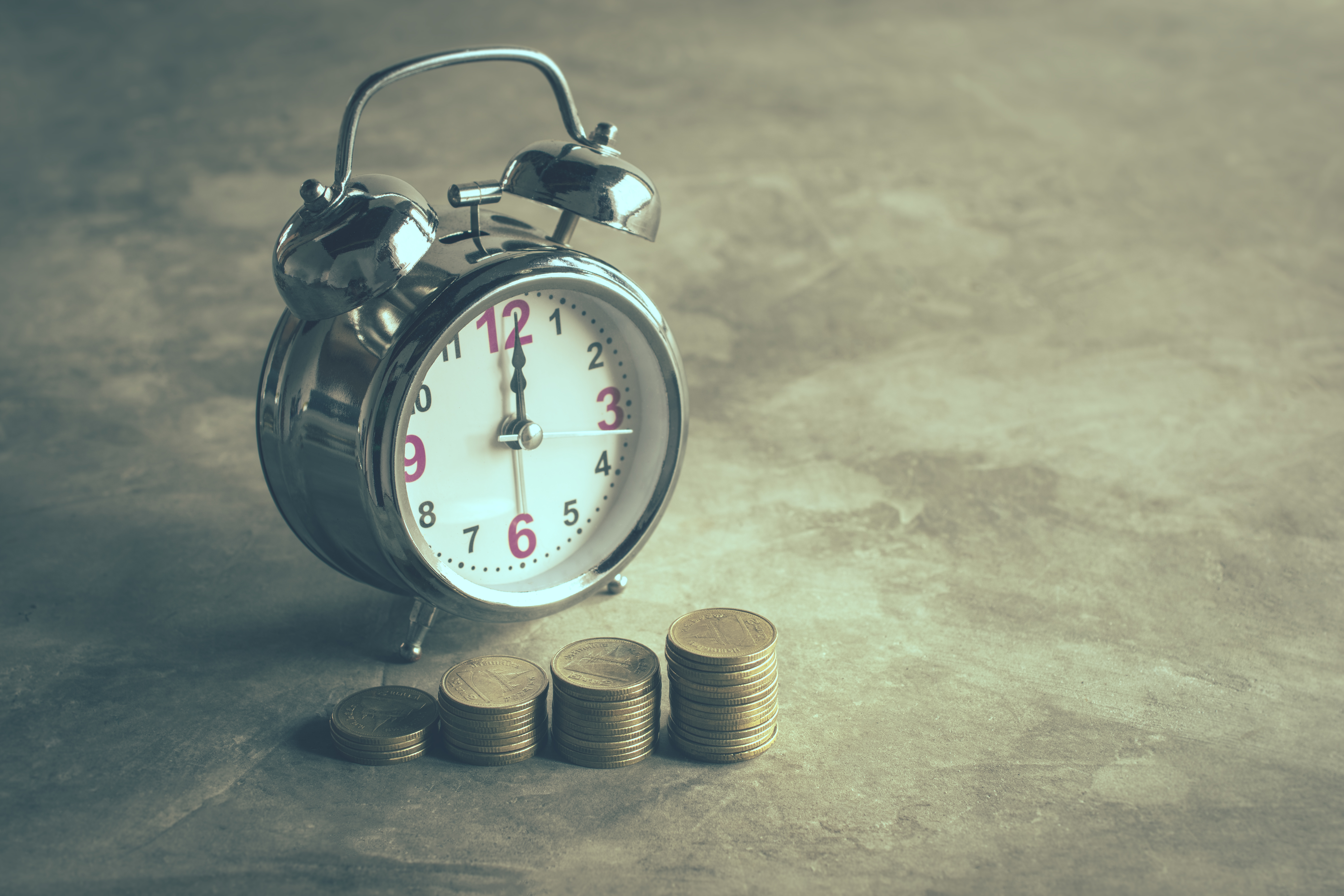 4 piles of coins in front of an alarm clock