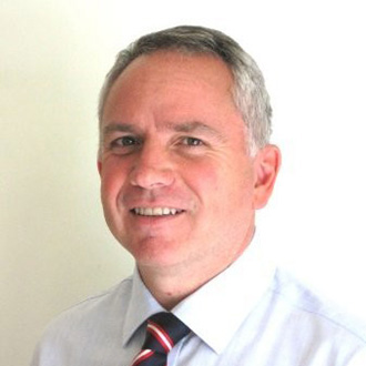 man in a shirt and tie smiling at the camera