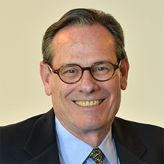 Man  with glasses in a suit smiling at the camera