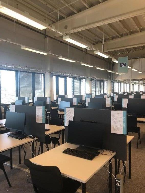 Colour photograph of the interior of the Exams Factory showing lines of screened desks with seats